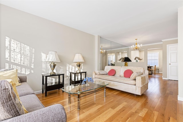 living room featuring light wood-style floors, baseboards, ornamental molding, and a notable chandelier