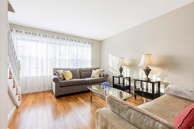 living area featuring baseboards, hardwood / wood-style floors, and stairs