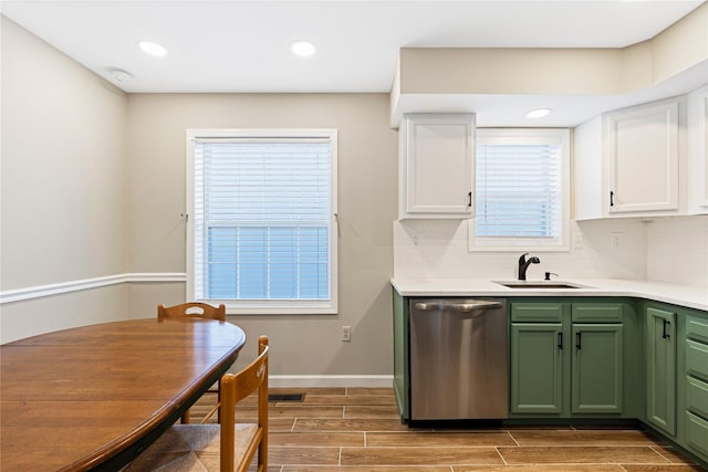 kitchen with green cabinets, wood tiled floor, white cabinets, a sink, and dishwasher