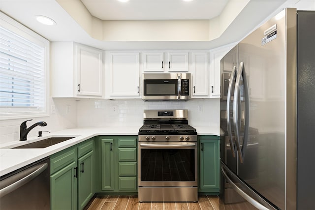 kitchen with stainless steel appliances, white cabinets, a sink, and green cabinets