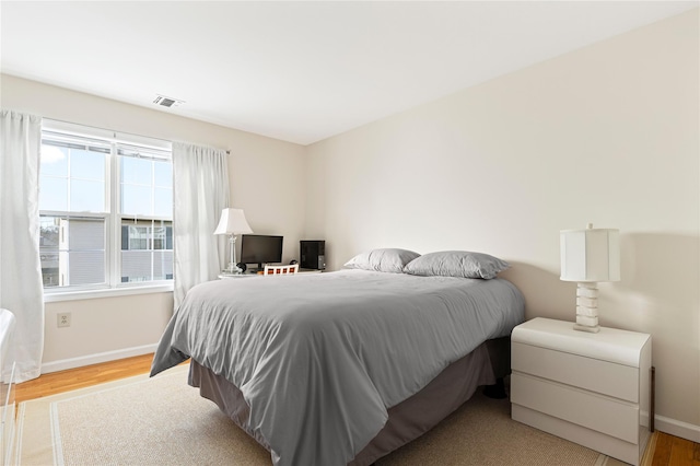 bedroom featuring visible vents, baseboards, and wood finished floors