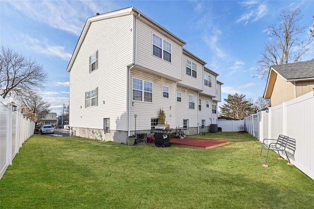 rear view of house featuring a deck, a lawn, cooling unit, and a fenced backyard