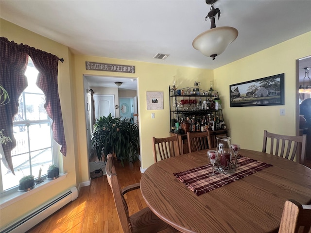 dining room featuring plenty of natural light, a baseboard radiator, visible vents, and light wood finished floors