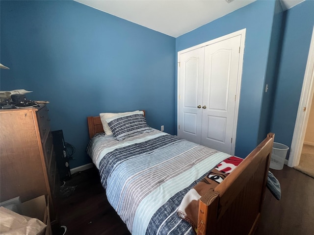 bedroom with dark wood-type flooring, a closet, and baseboards