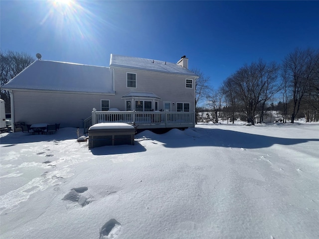 snow covered rear of property with a chimney and a deck