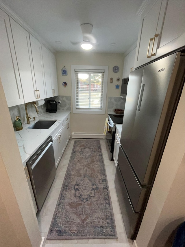 kitchen with stainless steel appliances, white cabinets, a sink, and light stone countertops