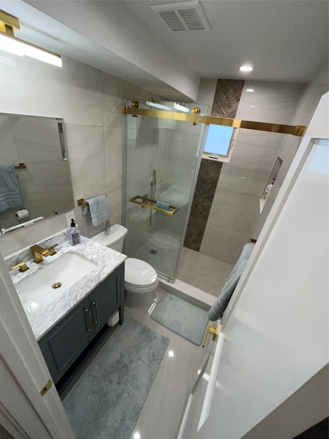 bathroom with toilet, a stall shower, visible vents, and vanity