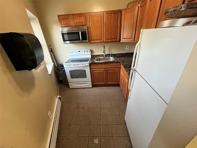 kitchen featuring white appliances, brown cabinetry, dark countertops, a baseboard radiator, and a sink