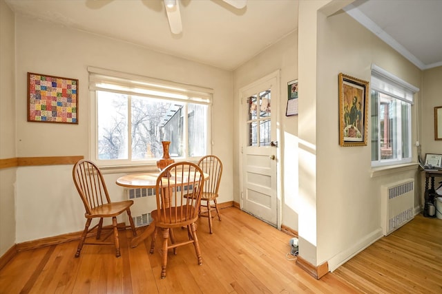 dining room with baseboards, a ceiling fan, light wood-style flooring, and radiator