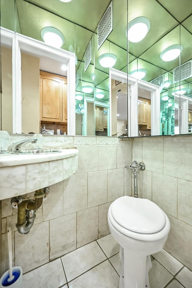 bathroom featuring toilet, tile walls, visible vents, and tile patterned floors