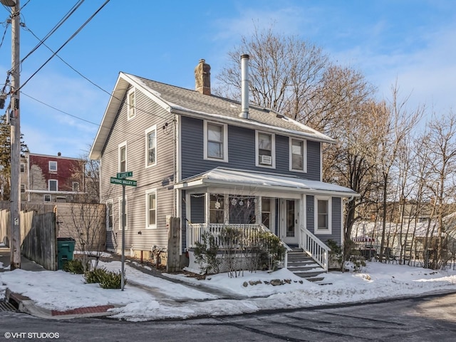 american foursquare style home with a chimney and a porch