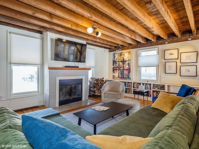 living area with radiator, wood finished floors, beamed ceiling, and a tile fireplace