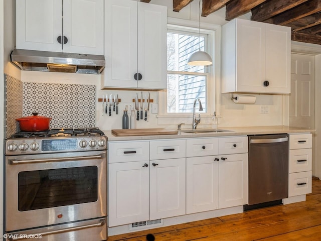 kitchen featuring stainless steel appliances, visible vents, light countertops, a sink, and under cabinet range hood