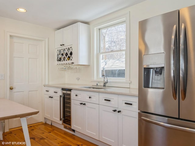 kitchen with light wood finished floors, white cabinets, wine cooler, light countertops, and stainless steel refrigerator with ice dispenser