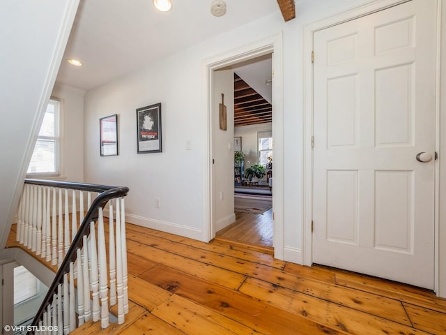 corridor with recessed lighting, light wood-style flooring, baseboards, and an upstairs landing