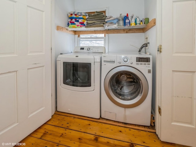 clothes washing area with washer and clothes dryer and light wood-style flooring