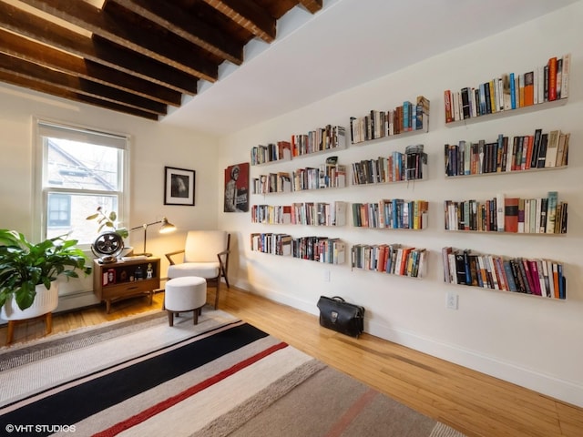 living area featuring wood finished floors, beam ceiling, and baseboards