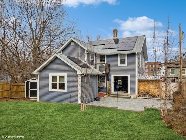 back of house with a patio area, a lawn, a fenced backyard, and solar panels