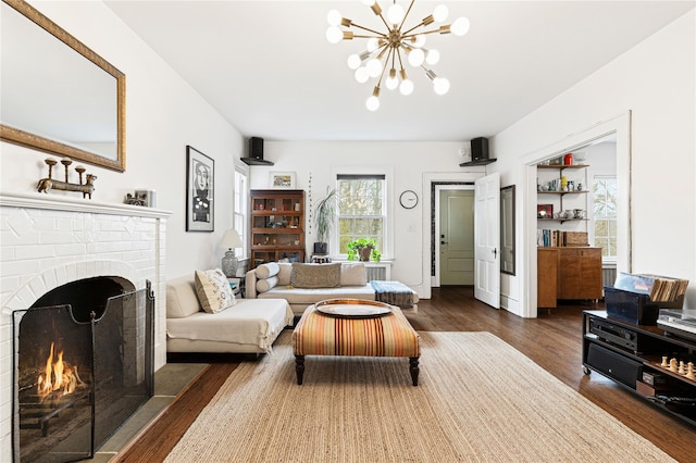 living room featuring a brick fireplace, dark wood-style floors, and a chandelier