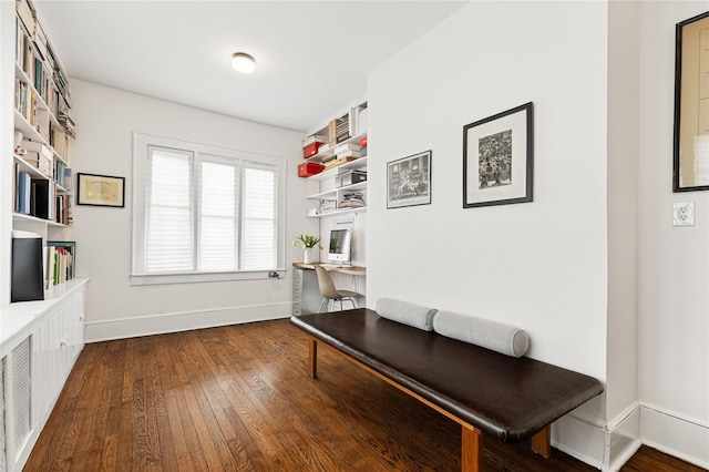 living area featuring baseboards, dark wood-style flooring, and built in study area