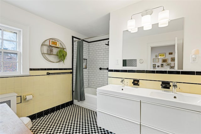 bathroom featuring tile walls, shower / washtub combination, double vanity, and a sink