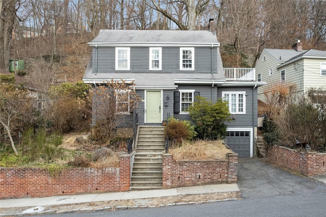 view of front of home featuring stairway, roof with shingles, driveway, a chimney, and a garage