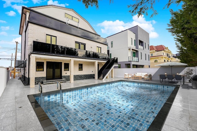 rear view of property featuring a fenced in pool, brick siding, fence, and a patio