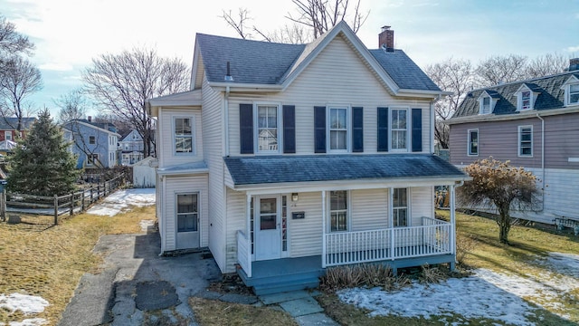 view of front of house featuring aphalt driveway, covered porch, fence, roof with shingles, and a chimney