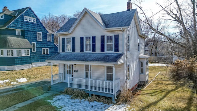 view of front of property featuring covered porch, a shingled roof, a chimney, and a front yard