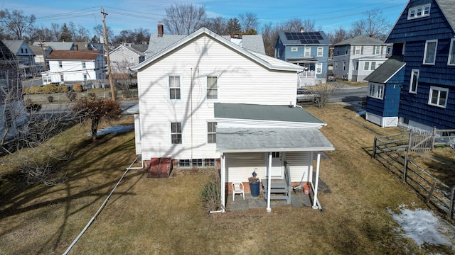 back of house with a yard, a residential view, roof with shingles, and fence