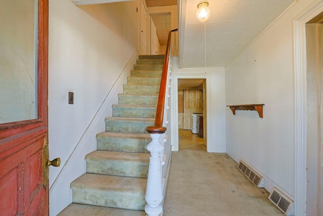 stairway with baseboards, crown molding, visible vents, and carpet flooring