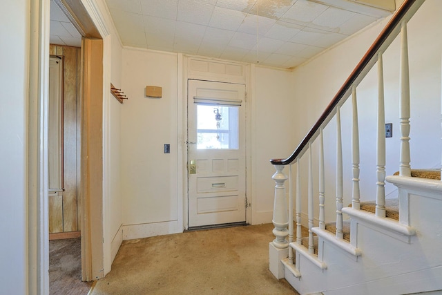 entryway with baseboards, stairway, and light colored carpet