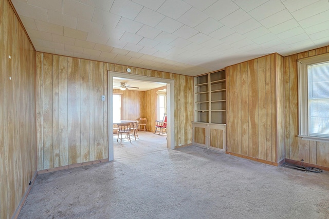 unfurnished room featuring wood walls, built in features, and carpet flooring