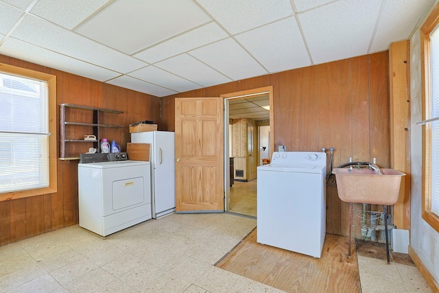 laundry room with laundry area, wooden walls, separate washer and dryer, and light floors