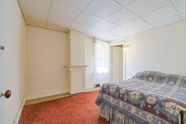 carpeted bedroom with a drop ceiling and baseboards