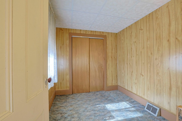 spare room featuring wood walls, carpet, and visible vents