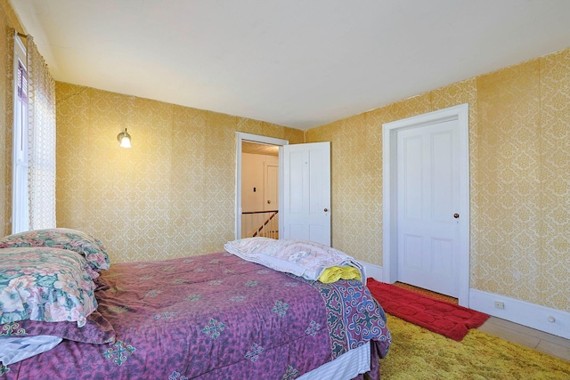 bedroom featuring baseboards and wallpapered walls