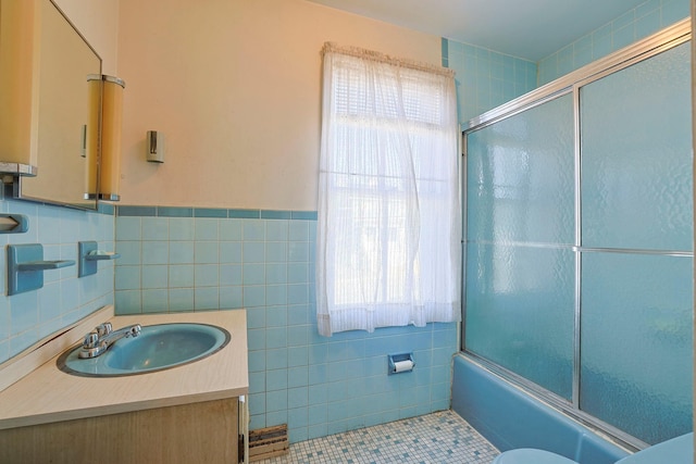 full bathroom featuring tile patterned flooring, combined bath / shower with glass door, tile walls, and vanity