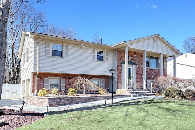 split foyer home featuring a front lawn, an attached garage, and brick siding