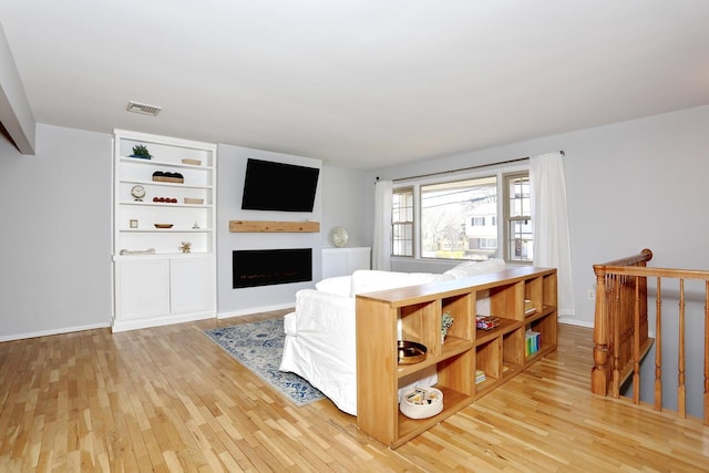 living room featuring visible vents, light wood-style floors, and a fireplace