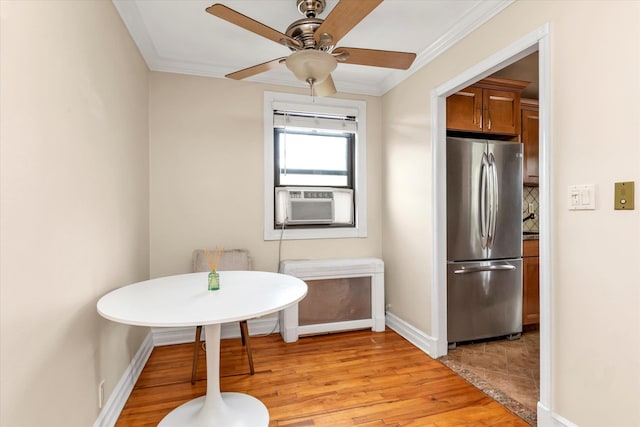 interior space featuring baseboards, a ceiling fan, cooling unit, crown molding, and light wood-type flooring