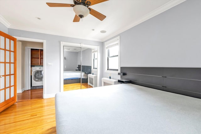 unfurnished bedroom featuring a closet, wood finished floors, washer / dryer, and crown molding