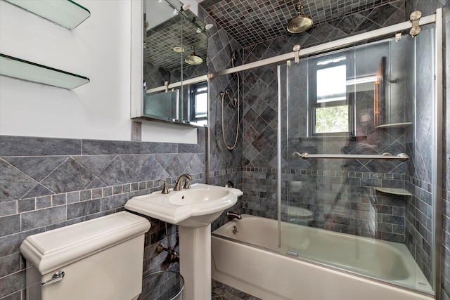 full bathroom with toilet, shower / bath combination with glass door, and tile walls