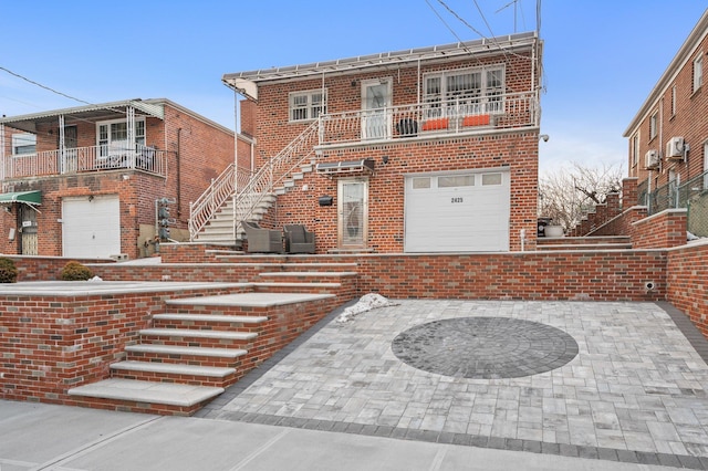 view of front of home with a balcony, a garage, stairs, and brick siding