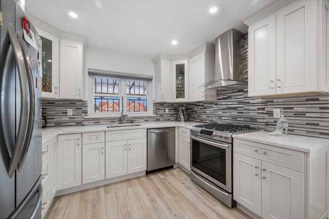 kitchen featuring glass insert cabinets, wall chimney range hood, appliances with stainless steel finishes, and white cabinets