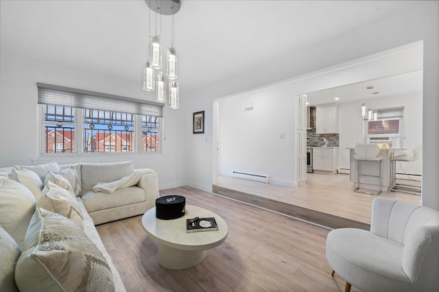 living area with a baseboard heating unit, light wood-type flooring, and baseboards