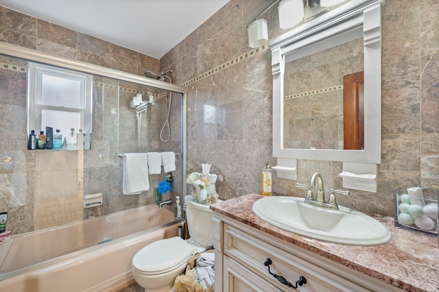 full bath with toilet, vanity, tile walls, combined bath / shower with glass door, and backsplash