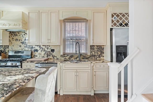 kitchen featuring custom range hood, light stone counters, cream cabinetry, a sink, and gas stove