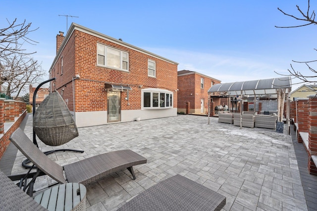 back of house featuring brick siding, a chimney, a patio area, and an outdoor living space