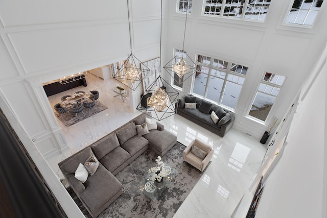 living area featuring an inviting chandelier, a towering ceiling, and a decorative wall